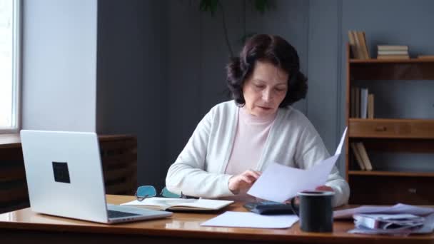 Oudere Vrouw Van Middelbare Leeftijd Zit Met Laptop Papieren Document — Stockvideo