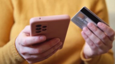 Kadının biri elinde akıllı telefonuyla alışveriş yapıyor ve kredi kartıyla ödeme yapıyor. İnternetten alışveriş yapan kızlar kredi kartı bilgilerini girerler. Çevrimiçi alışveriş ekommerce dağıtım servisi