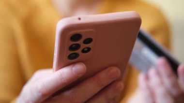 Kadının biri elinde akıllı telefonuyla alışveriş yapıyor ve kredi kartıyla ödeme yapıyor. İnternetten alışveriş yapan kızlar kredi kartı bilgilerini girerler. Çevrimiçi alışveriş ekommerce dağıtım servisi