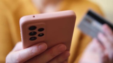 Kadının biri elinde akıllı telefonuyla alışveriş yapıyor ve kredi kartıyla ödeme yapıyor. İnternetten alışveriş yapan kızlar kredi kartı bilgilerini girerler. Çevrimiçi alışveriş ekommerce dağıtım servisi
