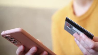 Kadının biri elinde akıllı telefonuyla alışveriş yapıyor ve kredi kartıyla ödeme yapıyor. İnternetten alışveriş yapan kızlar kredi kartı bilgilerini girerler. Çevrimiçi alışveriş ekommerce dağıtım servisi