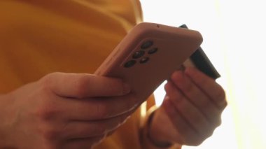 Kadının biri elinde akıllı telefonuyla alışveriş yapıyor ve kredi kartıyla ödeme yapıyor. İnternetten alışveriş yapan kızlar kredi kartı bilgilerini girerler. Çevrimiçi alışveriş ekommerce dağıtım servisi