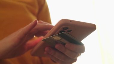 Kadının biri elinde akıllı telefonuyla alışveriş yapıyor ve kredi kartıyla ödeme yapıyor. İnternetten alışveriş yapan kızlar kredi kartı bilgilerini girerler. Çevrimiçi alışveriş ekommerce dağıtım servisi