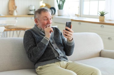 Arkadaşlarıyla video görüşmesinde orta yaşlı adam sohbetin kutlu olsun. Yaşlı, olgun büyükbabaya gülüp yetişkin çocuklarla internette konuşarak eğleniyor. Eski nesil modern teknoloji kullanımı