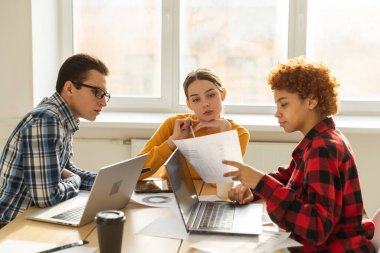 Takım çalışması beyin fırtınası. Çeşitli meslektaşlar birlikte çalışarak mali istatistikleri tartışırlar. Bir grup mutlu modern insan yaratıcı ofiste oturmuş iş tartışıyorlar. Genç profesyonel takım