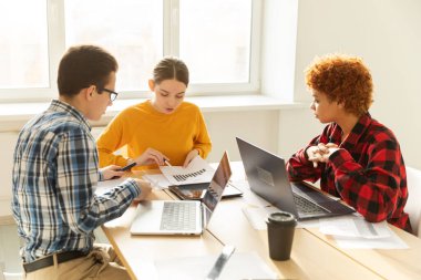 Takım çalışması beyin fırtınası. Çeşitli meslektaşlar birlikte çalışarak mali istatistikleri tartışırlar. Bir grup mutlu modern insan yaratıcı ofiste oturmuş iş tartışıyorlar. Genç profesyonel takım