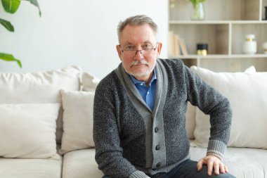 Evde kendine güveni tam orta yaşlı bir adam var. Yaşlı olgun 70 'lerin erkeği gülümsüyor. Mutlu, yaşlı ve sakallı büyükbaba kameraya bakıyor. Yüz portresi. Mutlu insanlar.