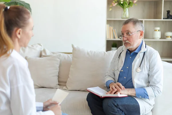 stock image Senior man doctor examining yound woman in doctor office or at home. Girl patient and doctor have consultation in hospital room. Medicine healthcare medical checkup. Visit to doctor