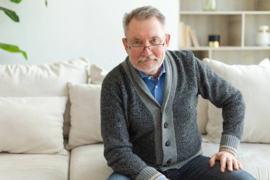 Evde kendine güveni tam orta yaşlı bir adam var. Yaşlı olgun 70 'lerin erkeği gülümsüyor. Mutlu, yaşlı ve sakallı büyükbaba kameraya bakıyor. Yüz portresi. Mutlu insanlar.