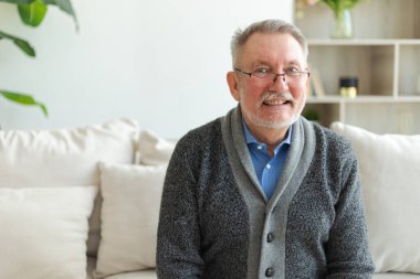 Evde kendine güveni tam orta yaşlı bir adam var. Yaşlı olgun 70 'lerin erkeği gülümsüyor. Mutlu, yaşlı ve sakallı büyükbaba kameraya bakıyor. Yüz portresi. Mutlu insanlar.