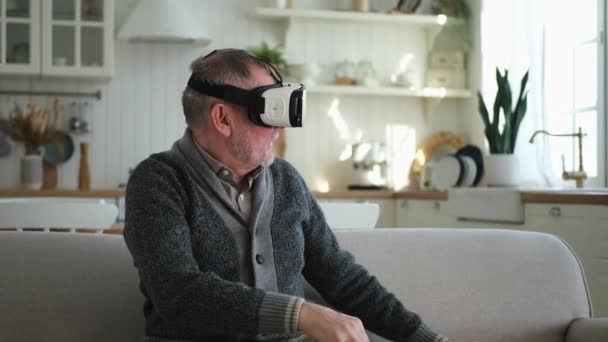兴奋而成熟的老年人在家里戴着虚拟现实变相Vr眼镜耳机 在虚拟现实头盔上的Vr体验中 祖父触摸空气 模拟高科技视频游戏 — 图库视频影像
