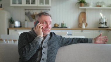 Mutlu orta yaşlı bir adam aile dostlarıyla akıllı telefondan konuşuyor. Yetişkin bir büyükbaba cep telefonuyla yetişkin çocuklarla konuşuyor, evde dinleniyor. Eski nesil modern teknoloji kullanımı