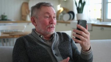 Arkadaşlarıyla video görüşmesinde orta yaşlı adam sohbetin kutlu olsun. Yaşlı, olgun büyükbabaya gülüp yetişkin çocuklarla internette konuşarak eğleniyor. Eski nesil modern teknoloji kullanımı
