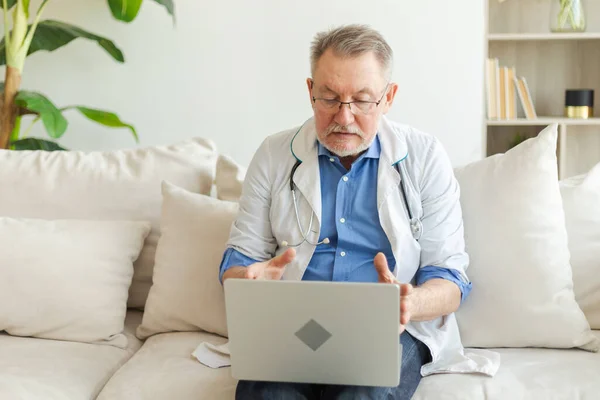 Senior man doctor with laptop talk on video call have consultation with patient. Professional senior mature healthcare expert examining patient online. Medicine healthcare medical checkup