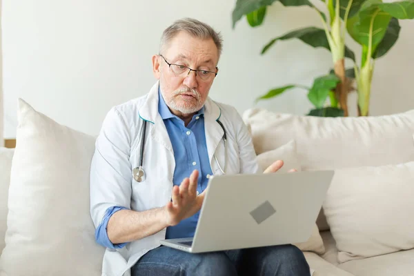 Senior man doctor with laptop talk on video call have consultation with patient. Professional senior mature healthcare expert examining patient online. Medicine healthcare medical checkup