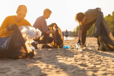 Dünya günü. Gönüllü eylemciler, sahil bölgesindeki çöpleri topluyor. Bir grup insan okyanus kıyısındaki çöp torbalarına plastik çöp koyuyor. Çevresel koruma