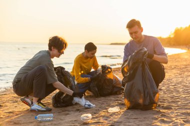 Dünya günü. Gönüllü eylemciler, sahil bölgesindeki çöpleri topluyor. Bir grup insan okyanus kıyısındaki çöp torbalarına plastik çöp koyuyor. Çevresel koruma