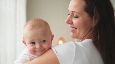 Evde mutlu bir aile. Anne kucağında küçük bir kız çocuğu. Anne ve bebek evde birlikte oynayarak rahatlar. Anne bebeğe sevgiyle sarılır. Bebeği emziren anne.