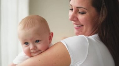 Evde mutlu bir aile. Anne kucağında küçük bir kız çocuğu. Anne ve bebek evde birlikte oynayarak rahatlar. Anne bebeğe sevgiyle sarılır. Bebeği emziren anne.