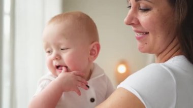 Evde mutlu bir aile. Anne kucağında küçük bir kız çocuğu. Anne ve bebek evde birlikte oynayarak rahatlar. Anne bebeğe sevgiyle sarılıyor. Bebeği emziren anne.