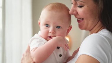 Evde mutlu bir aile. Anne kucağında küçük bir kız çocuğu. Anne ve bebek evde birlikte oynayarak rahatlar. Anne bebeğe sevgiyle sarılıyor. Bebeği emziren anne.