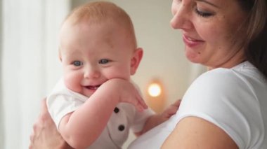 Evde mutlu bir aile. Anne kucağında küçük bir kız çocuğu. Anne ve bebek evde birlikte oynayarak rahatlar. Anne bebeğe sevgiyle sarılır. Bebeği emziren anne.