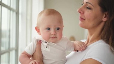 Evde mutlu bir aile. Anne kucağında küçük bir kız çocuğu. Anne ve bebek evde birlikte oynayarak rahatlar. Anne bebeğe sevgiyle sarılır. Bebeği emziren anne.
