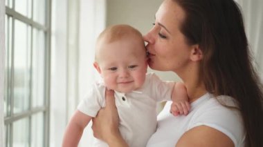 Evde mutlu bir aile. Anne kucağında küçük bir kız çocuğu. Anne ve bebek evde birlikte oynayarak rahatlar. Anne bebeğe sevgiyle sarılıyor. Bebeği emziren anne.