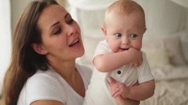Evde mutlu bir aile. Anne kucağında küçük bir kız çocuğu. Anne ve bebek evde birlikte oynayarak rahatlar. Anne bebeğe sevgiyle sarılır. Bebeği emziren anne.
