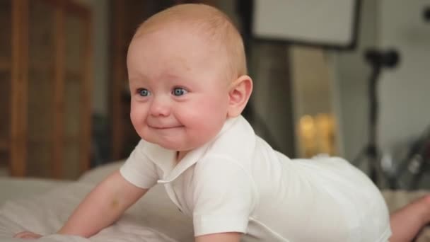 ハッピーベイビー ベッドルームのベッドで笑顔でかわいい小さな新生児 赤ん坊は家で毛布の上に横たわって遊んでいます 母性幸せな育児コンセプト — ストック動画