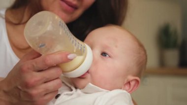 Evde mutlu bir aile. Anne kucağında küçük bir bebek, sütü şişeden besliyor. Yeni doğmuş bebek kız bebek süt içiyor. Bebeği emziren anne. Annelik mutlu çocuk