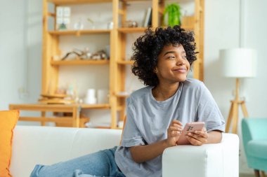 Akıllı telefon tutan Afrikalı bir kız. Evde parşömen sayfasına dokunuyor. Sosyal medya uygulamaları kullanarak internette cep telefonu sörfü yapan bir kadın. İnternet üzerinden haber alışverişi cep telefonu bağımlılığı