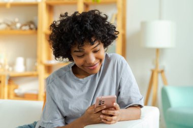 Akıllı telefon tutan Afrikalı bir kız. Evde parşömen sayfasına dokunuyor. Sosyal medya uygulamaları kullanarak internette cep telefonu sörfü yapan bir kadın. İnternet üzerinden haber alışverişi cep telefonu bağımlılığı