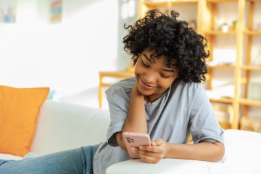 Akıllı telefon tutan Afrikalı bir kız. Evde parşömen sayfasına dokunuyor. Sosyal medya uygulamaları kullanarak internette cep telefonu sörfü yapan bir kadın. İnternet üzerinden haber alışverişi cep telefonu bağımlılığı