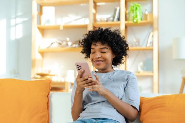 Akıllı telefon tutan Afrikalı bir kız. Evde parşömen sayfasına dokunuyor. Sosyal medya uygulamaları kullanarak internette cep telefonu sörfü yapan bir kadın. İnternet üzerinden haber alışverişi cep telefonu bağımlılığı