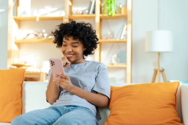 Akıllı telefon tutan Afrikalı bir kız. Evde parşömen sayfasına dokunuyor. Sosyal medya uygulamaları kullanarak internette cep telefonu sörfü yapan bir kadın. İnternet üzerinden haber alışverişi cep telefonu bağımlılığı