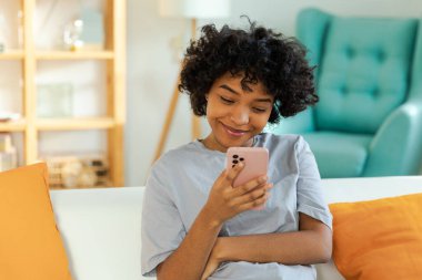Akıllı telefon tutan Afrikalı bir kız. Evde parşömen sayfasına dokunuyor. Sosyal medya uygulamaları kullanarak internette cep telefonu sörfü yapan bir kadın. İnternet üzerinden haber alışverişi cep telefonu bağımlılığı