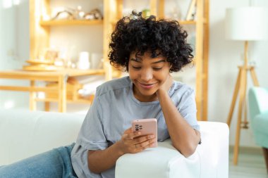 Akıllı telefon tutan Afrikalı bir kız. Evde parşömen sayfasına dokunuyor. Sosyal medya uygulamaları kullanarak internette cep telefonu sörfü yapan bir kadın. İnternet üzerinden haber alışverişi cep telefonu bağımlılığı