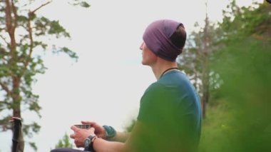 Uçuruma tırmanma macerası. Gezintiden sonra güzel manzaraya bakan sırt çantalı adam dinleniyor. Sırt çantalı bir turist göl kenarındaki büyük bir kayanın üzerinde oturuyor. Yürüyüşçü adam turizmin tadını çıkarıyor.