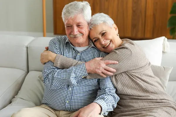 Senior adult mature couple hugging at home. Mid age old husband and wife embracing with tenderness love enjoying sweet bonding wellbeing. Grandmother grandfather together. Family moment love and care