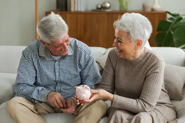 Saving money investment for future. Senior adult mature couple holding piggy bank putting money coin. Old man woman counting saving money planning retirement budget. Saving investment banking concept