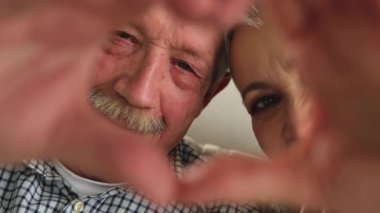 Aşk, barışı şekillendirir. Yaşlı çift elleriyle kalp şekli yaratıyor. Yetişkin, olgun koca eşi kalp işareti gösteriyor. Mutlu emekliler ailesi. Seni seviyorum Sevgililer Günü 'n kutlu olsun