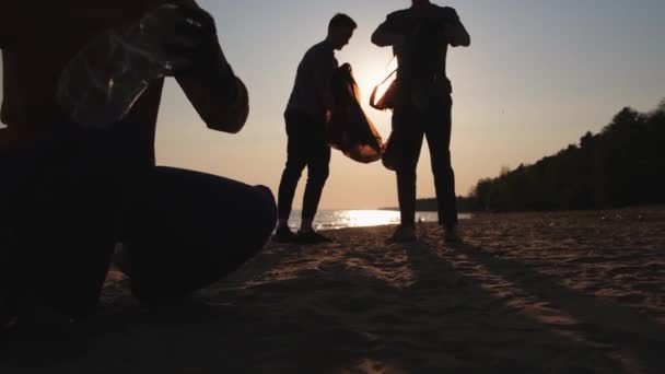 地球日志愿人员积极收集海滩沿岸地区的垃圾清理 女人和男人把塑料垃圾放在海滨的垃圾袋里 环境保护及沿海区清洁 — 图库视频影像