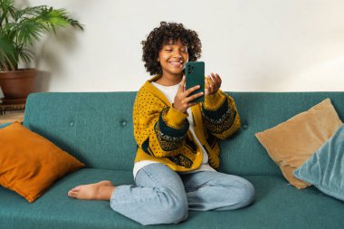 Afrika kökenli Amerikalı bir kız elinde akıllı telefonuyla görüntülü konuşma yapıyor. Kadın blogcu sosyal ağdaki en iyi arkadaşlarıyla sohbet ediyor. Genç bir kadın internette görüntülü görüşme yapıyor.