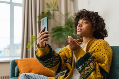 African american girl holding smartphone having video chat. Female blogger chatting with best friends in social network. Young woman having virtual meeting online chat video call at home