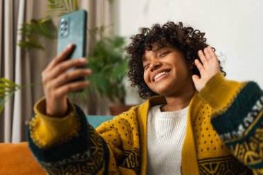 African american girl holding smartphone having video chat. Female blogger chatting with best friends in social network. Young woman having virtual meeting online chat video call at home