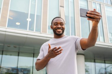 Afro-Amerikalı bir adam elinde akıllı telefonuyla şehirdeki bir caddede görüntülü konuşma yapıyor. Blogcu sosyal ağda en iyi arkadaşlarıyla sohbet ediyor. İnternette sanal görüşme yapan bir adam görüntülü konuşma yapıyor.