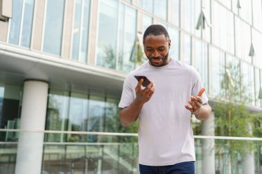 Açık havada, sokakta akıllı telefondan konuşan Afrikalı Amerikalı bir adam. Cep telefonlu bir adam arkadaşlarıyla sohbet ediyor. Gülümseyen kişi cep telefonuyla cevap veriyor. Cep telefonuyla konuşan adam