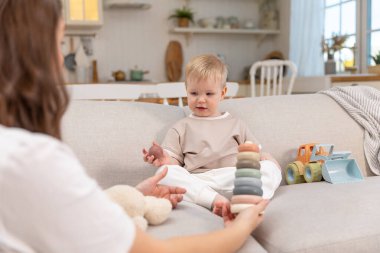 Evde mutlu bir aile. Anne ve bebek evdeki kanepede oyuncaklarla oynuyor. Küçük çocuk ve bebek bakıcısı birlikte eğleniyorlar. Genç kadın, anne, çocuk oturma odasında dinleniyor.