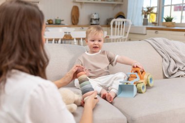 Evde mutlu bir aile. Anne ve bebek evdeki kanepede oyuncaklarla oynuyor. Küçük çocuk ve bebek bakıcısı birlikte eğleniyorlar. Genç kadın, anne, çocuk oturma odasında dinleniyor.
